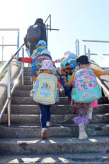 Children in backpacks walking up stairs at the exhibition